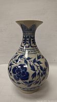 Front view of the hand painted antique vase showing floral and geometric blue designs on white porcelain.