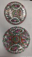 Top view of both hand painted glazed porcelain plates showing detailed colorful designs and sizes.
