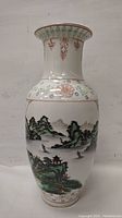 Front view of the vase showing hand painted Asian mountain landscape with pagodas and boats.