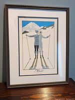 Full view of framed Art Deco skiing couple print under glass, featuring a snowy mountain scene with a kissing couple in skiing attire.