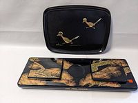 Two black lacquer trays, one with two small birds and the other rectangular with gold pine design and smaller trays on top
