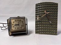 Front and side view of the smaller Sunbeam clock next to the larger untested clock showing overall condition and design details.