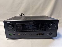 Front view of black Denon AVR-588 receiver displaying digital settings with volume and input knobs, power button lit green, and audio input jacks visible.