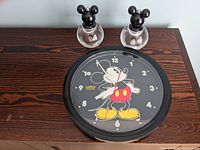 Photo showing the Mickey Mouse quartz clock with a black frame and character image face alongside the two acrylic salt and pepper grinders.