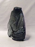 Front view of the grey glass sculpture showing its textured, irregular, abstract form and glossy surface.