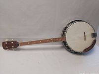 Full length side view of the banjo revealing neck, drum head, and headrest