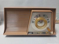 Front view of vintage Motorola tube radio showing speaker grille and tuning dial with frequency markings and Motorola logo.