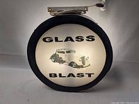 Front view of circular illuminated retail store sign showing the text 'GLASS BLAST' and vintage car graphic in the center.