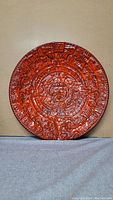 Front view of the 16 inch Aztec themed serving plate showing detailed calendar design and reddish glaze.