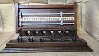 Full view of wooden pool cue holder and attached scoreboard with metal sliders showing numerical score range 0-100.