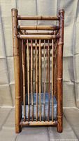 Front view of vintage bamboo umbrella stand showing vertical bamboo slats and metal drip tray.