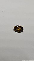 Oval cut deep golden yellow sapphire gemstone on a white background.