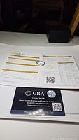 Opened GRA certificate letter with warranty card on white background