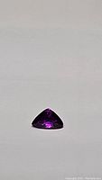 Trillion cut pink-purple sapphire gemstone on white background, face view