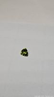 Top view photo of the apple green peridot gemstone showing its trillion cut shape and clarity.