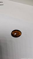 Oval double sided Madeira citrine gemstone with checkerboard cut, showing deep whiskey color on white background.