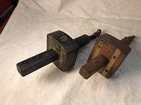 Two wooden butt gauges with square blocks and rectangular shafts, showing signs of use and metal screws at the end.