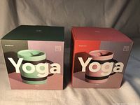 Two boxes labeled 'Yoga' showing the packaging of each mug, one greenish and one pinkish box