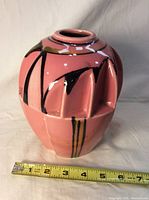 Front view of pink deco style flower vase with tape measure showing 7 inch height approximately.