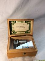 Open music box showing the internal cylinder and comb with a label on the lid listing songs and model details.
