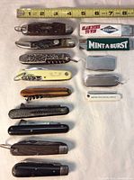 Top view of 11 pocket cutting tools arranged next to a measuring tape for size reference.