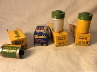 Three Kodak 35MM film boxes and two green-topped plastic film cannisters, along with one box of Black's slide film.