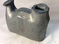 Side view of the closed metal chocolate mold shaped like a house, showing a smooth back surface and hinge detail on top.