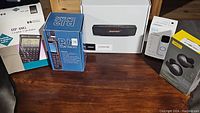 Front view of all boxed items: HP 48G calculator, PJ2 com radio, Bose SoundLink Mini II, Blink doorbell, Jabra Elite 65t box.
