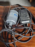 View of the gray Pro-Craft motor unit with attached cables and foot control placed on a wooden surface.