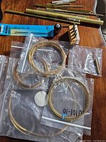 Top view of assorted metal rods and coiled wires in plastic bags on a wooden surface.