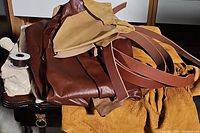 Various pieces of smooth and suede leather in brown, tan, and mustard yellow colors laid out showing texture and colors.