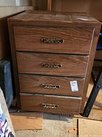 Front view of wood veneer cabinet with four drawers featuring metal handles. Visible scratches and wear on drawer fronts.