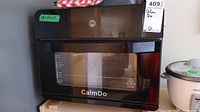 Front view of CalmDo oven with visible brand logo and measurement lines on glass door.