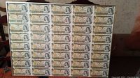 Full view of framed uncut sheet showing all 40 one-dollar bills and cracked glass