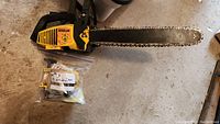 Yellow McCulloch Wildcat chainsaw with bar and chain on concrete floor, bag of parts included