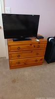Front view of pine dresser with TV on top showing wear and drawer pulls.