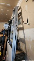 Side view of folded 6-foot metal ladder leaning against a wall in a garage setting.