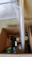 Box contents showing paint roller, plastic sheeting, paint cans inside box from top angle