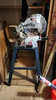 Front view of the Craftsman 10-inch laser compound miter saw mounted on its metal stand in a garage environment.