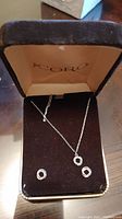 Photo showing sterling silver necklace with round pendant and matching circular stud earrings in velvet box