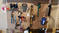 Full view of tool assortment hung on garage pegboard including screwdrivers, wrenches, pliers, ratchets, and levels