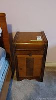 Front view of vintage Art Deco waterfall style wood night stand with single drawer and cabinet door beneath, showing wood finish and handle details.