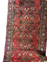 Close-up of runner rug showing red field with floral motifs and decorative border