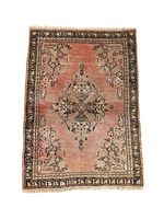 Front view of rectangular Hamedan backrest in pinkish natural colors with floral central medallion and black geometric border. Fringe visible.