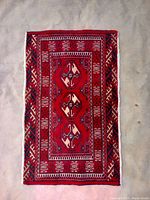 Full top view of the rectangular Turkmen backrest rug showing the overall red field with central three octagonal gul medallions and surrounding borders.