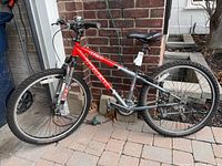 Full side view of red and gray Trek 820 mountain bike leaning against brick wall.