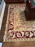 Corner view showing burgundy border, floral motifs, light center field and desk placement on hardwood floor