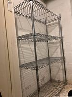 Full view of four-tier metal wire shelving rack showing overall structure, chrome finish, and adjustable shelf positions.