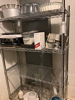 Full view of metal wire shelving unit with four shelves, items on shelves are not included in the lot.