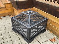 Overall assembled fire pit on paved patio against wooden backdrop